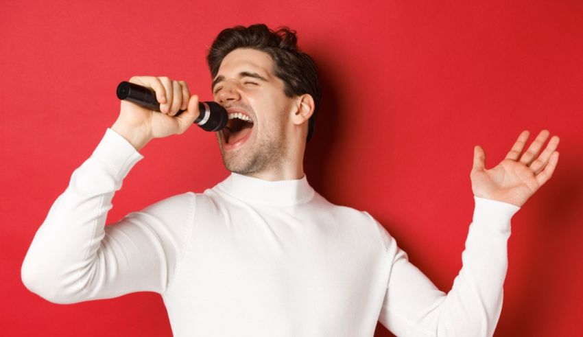 A man singing into a microphone against a red background.
