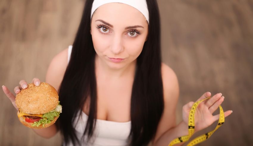 A woman holding a burger and measuring tape.