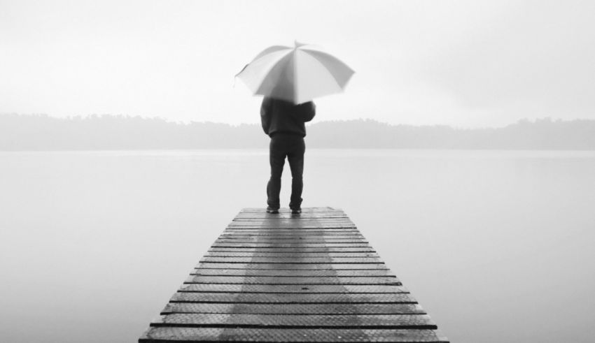 A person standing on a dock with an umbrella.