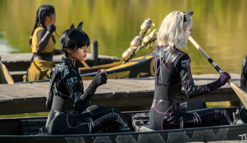 A group of women in catsuits paddling in a canoe.