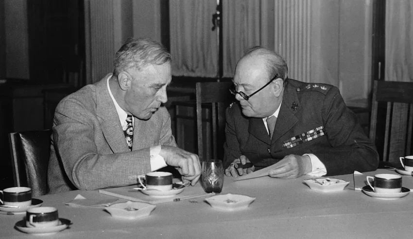 Two men sitting at a table with cups and saucers.