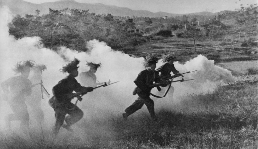 A group of soldiers with guns running through a field.