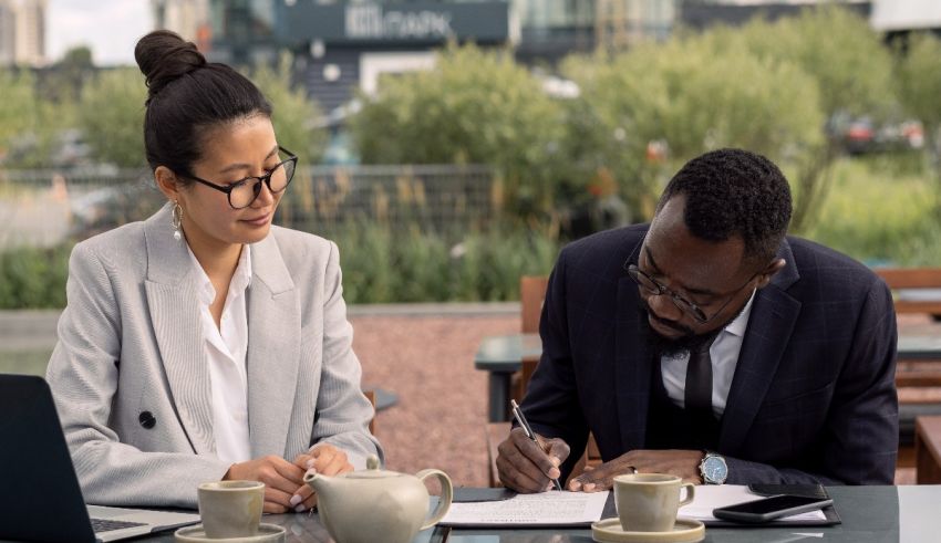 Two business people sitting at a table and signing documents.