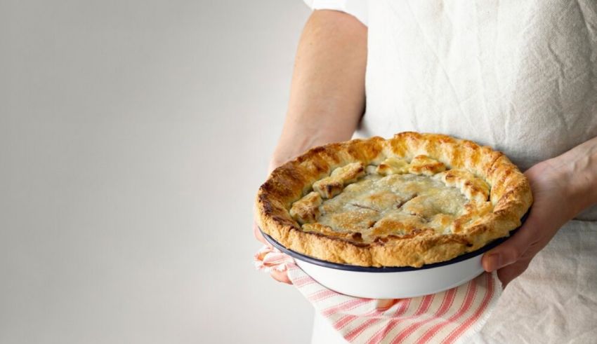 A woman holding a pie in a bowl.
