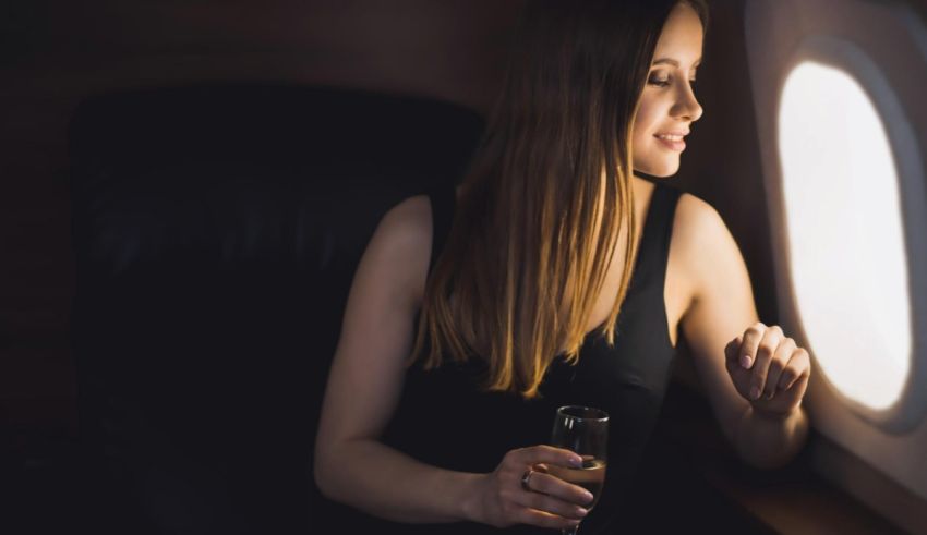 A woman is sitting in an airplane with a glass of wine.