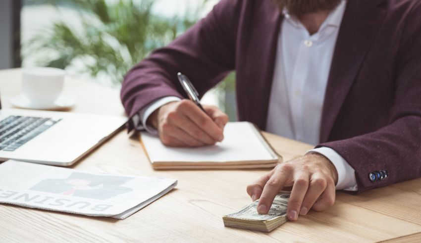 A man sitting at a desk with money and a notebook.