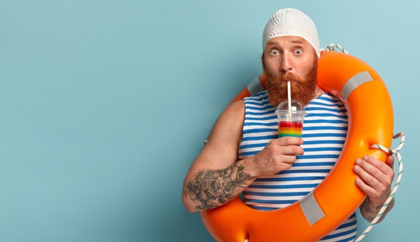 A bearded man with a life preserver holding a drink.