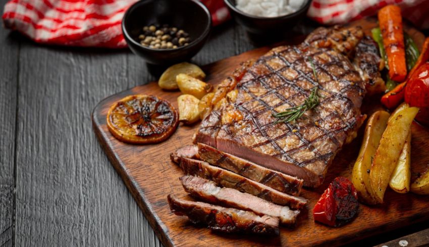 Steak and vegetables on a wooden cutting board.