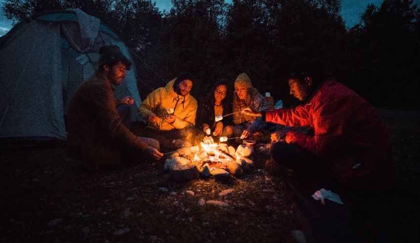 A group of people sitting around a campfire at night.