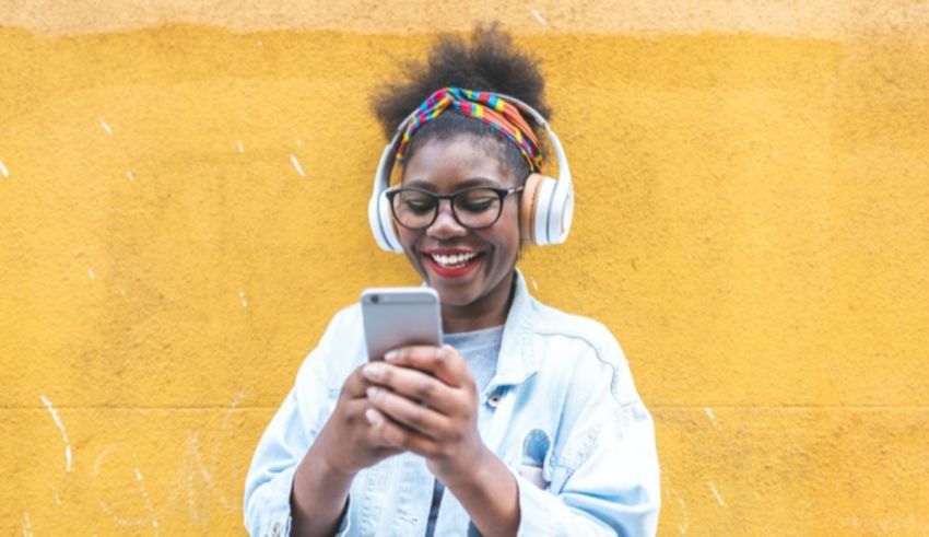 A black woman wearing headphones and listening to music on her phone.