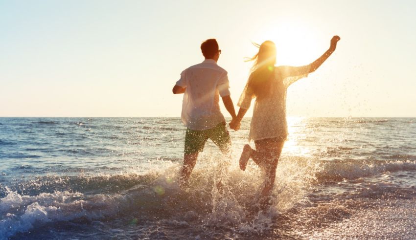 A man and woman are running in the water at the beach.