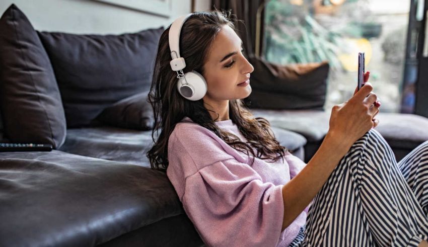 A woman wearing headphones is sitting on a couch.