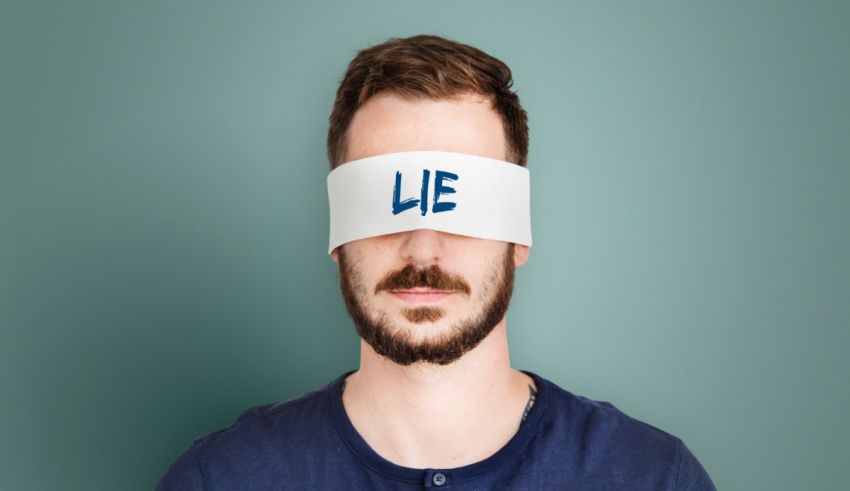 A man with a blindfold covering his eyes with the word lie.