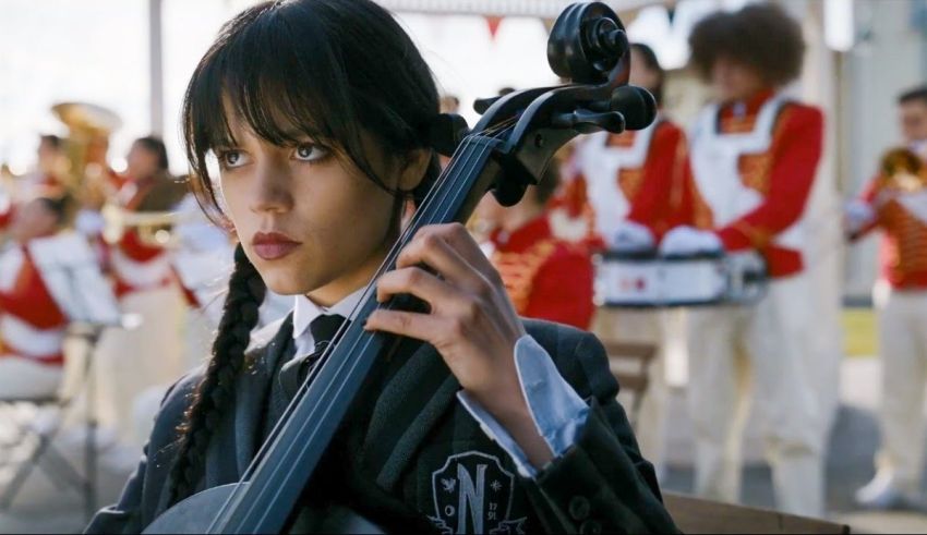 A young girl playing a cello in front of a band.