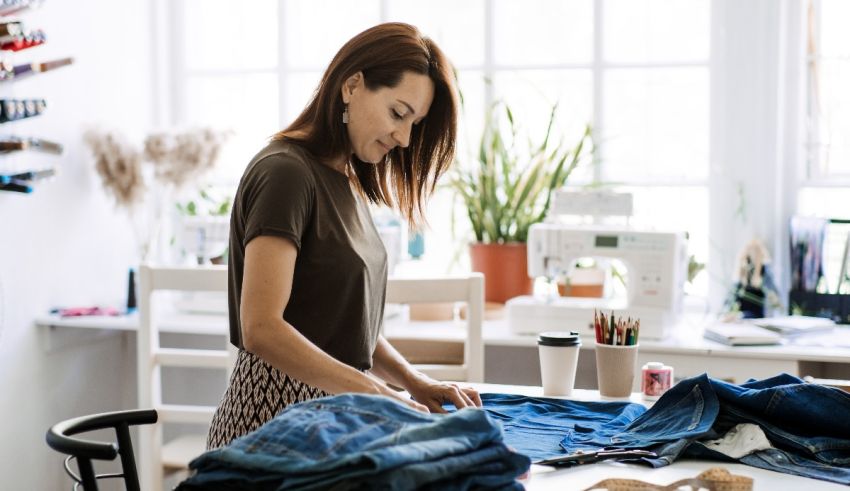 A woman is working on a pair of jeans in a sewing room.