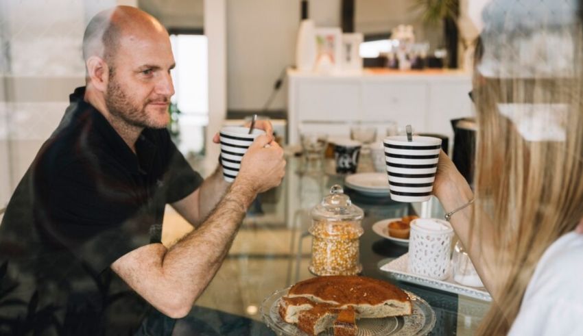 A man and woman sitting at a table eating breakfast.