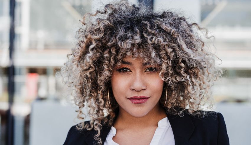 A woman with curly hair standing in front of a building.