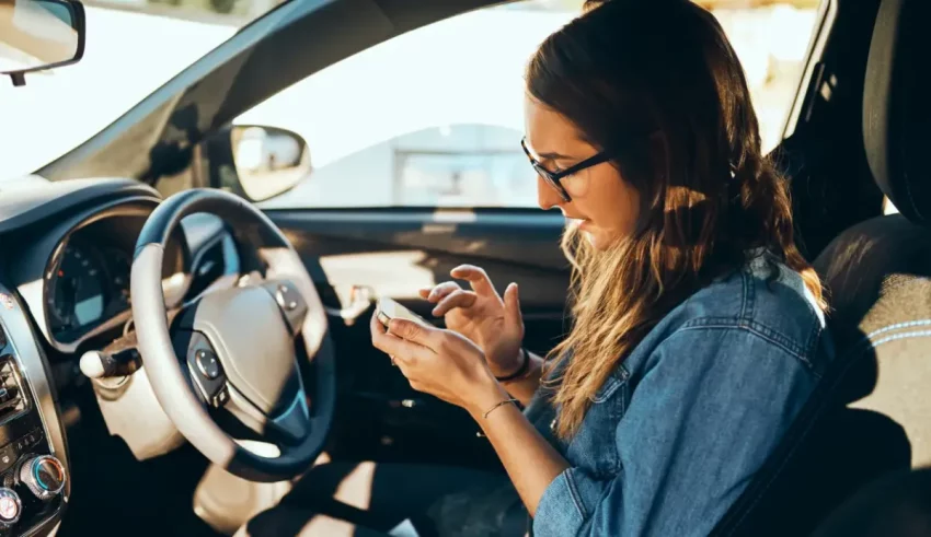 A woman in a car using her cell phone.