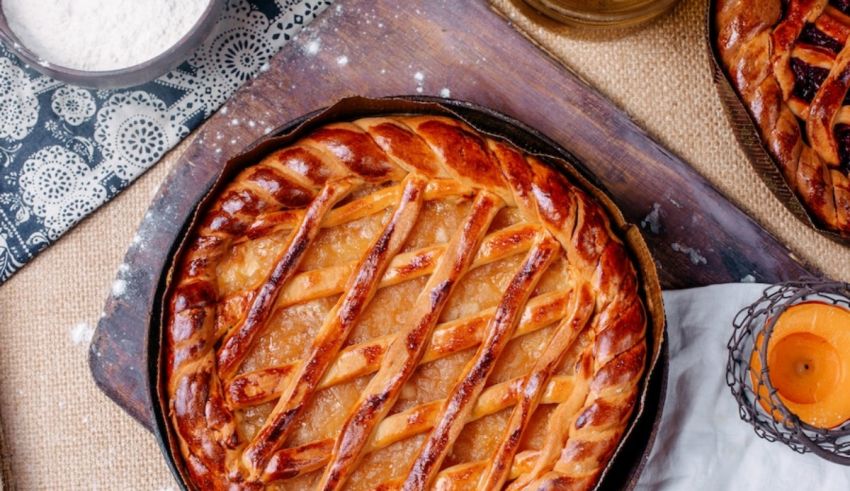 A pie with a lattice pattern in a pan on a wooden table.