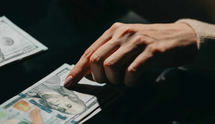 A woman's hand is holding a stack of dollar bills.