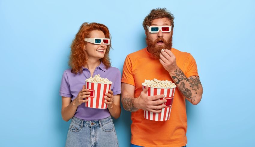 A man and woman wearing 3d glasses are watching a movie on a blue background.