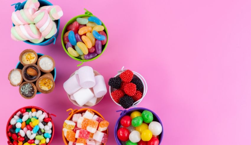 Colorful bowls of candy on a pink background.