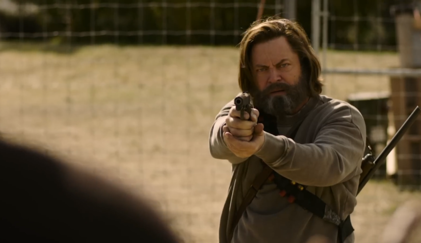 A man with long hair holding a gun.