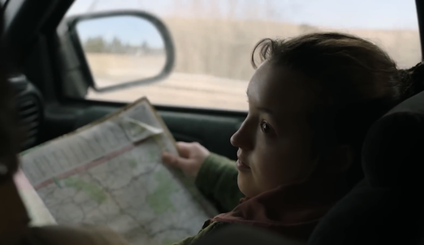 A young girl looking at a map in the back seat of a car.
