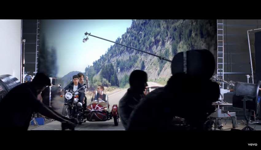 A group of people on a motorcycle in front of a camera.
