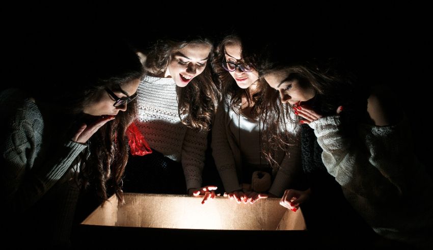 A group of girls looking at a box in the dark.