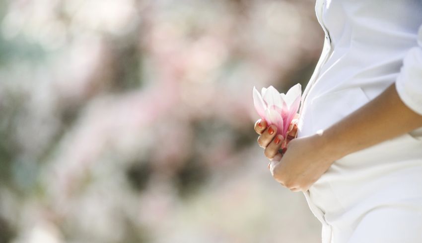 A pregnant woman holding a flower in her stomach.