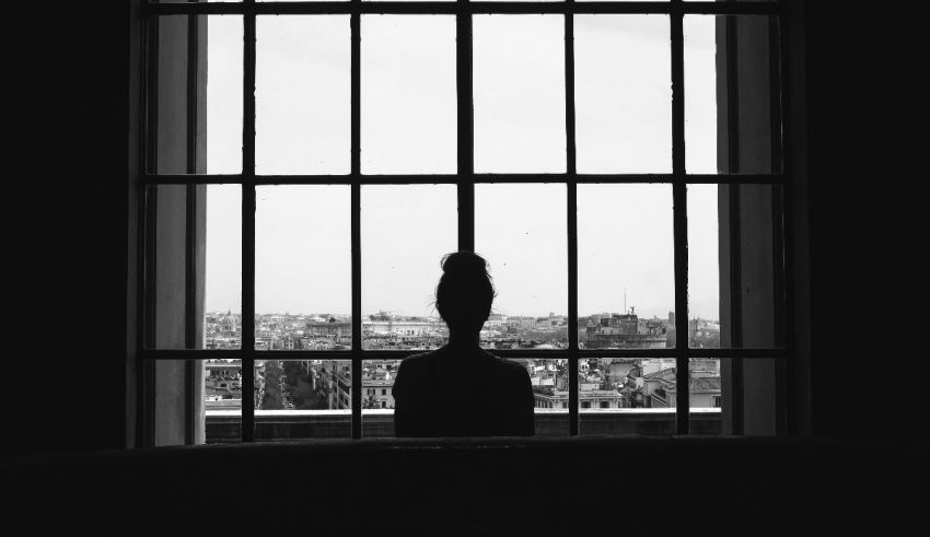 A black and white photo of a woman looking out of a window.