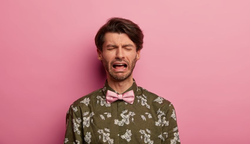 A man in a pink shirt is yelling against a pink background.