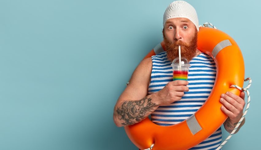 A bearded man with a life preserver holding a drink.