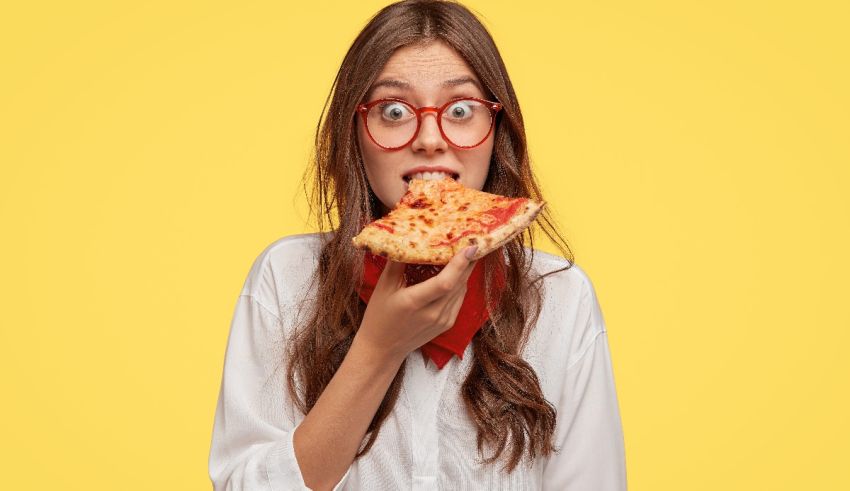 A woman eating a slice of pizza on a yellow background.