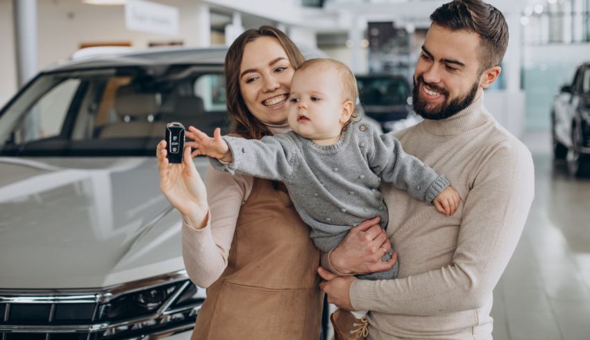 A family with a baby in front of a car dealership.