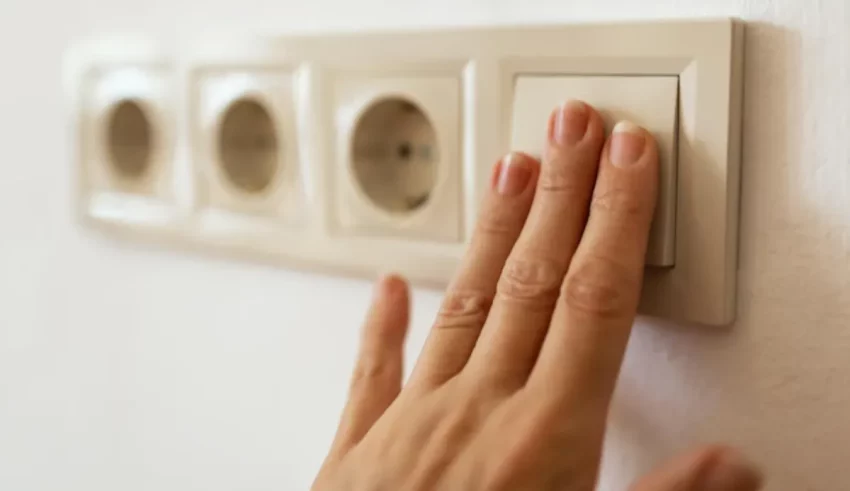 A woman's hand is touching an electrical outlet.