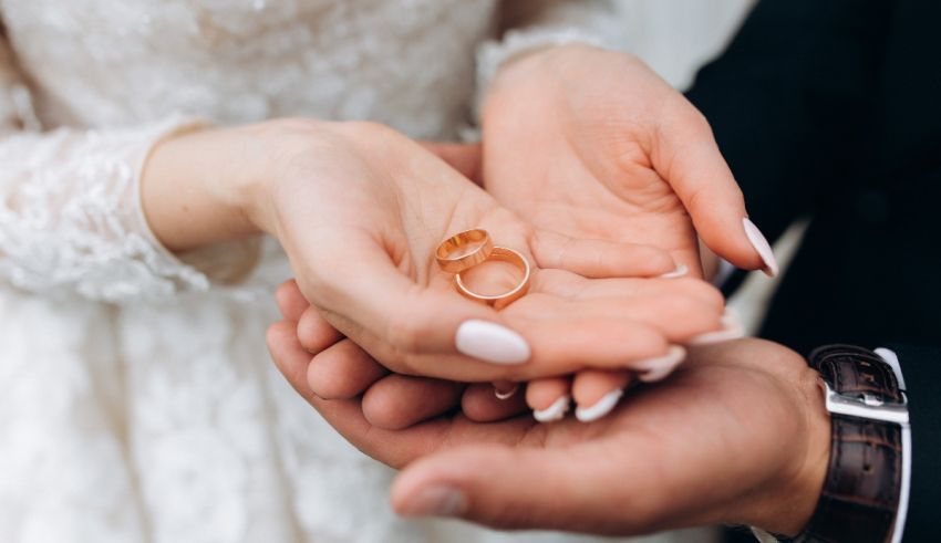 A bride and groom holding wedding rings in their hands.
