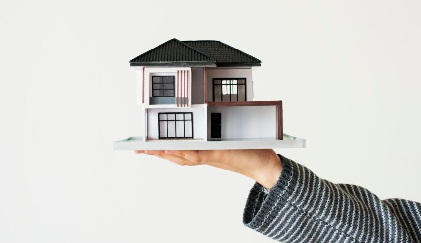 A person holding a model of a house on a white background.
