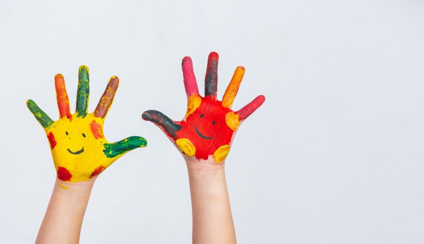 Two children's hands with colorful paint on them.