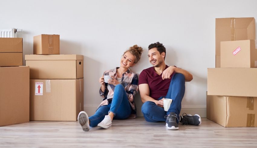 Young couple sitting on the floor in front of moving boxes.
