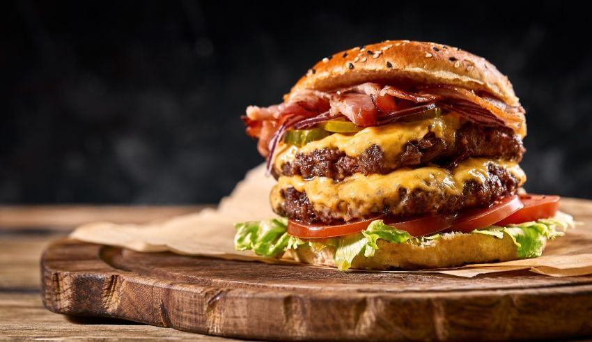 A burger with bacon and cheese on top of a wooden board.