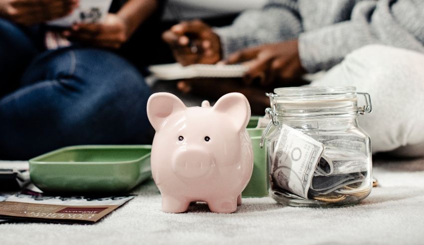 People sitting on the floor with a pink piggy bank and money.