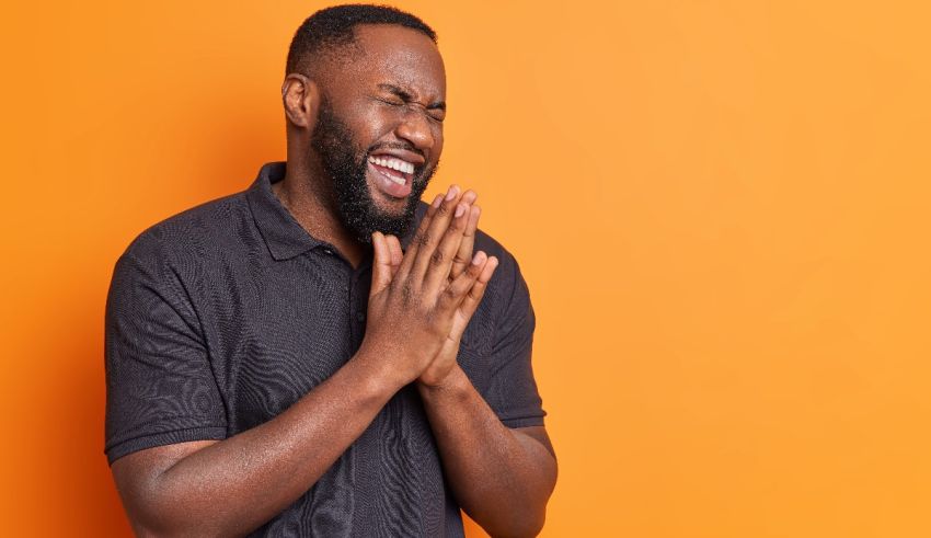 A black man is clapping his hands against an orange background.