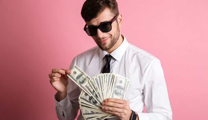 A young man wearing sunglasses and a tie holding a stack of dollar bills.