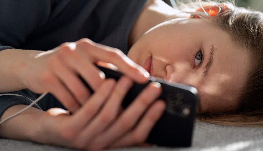 A girl laying on the floor looking at her phone.