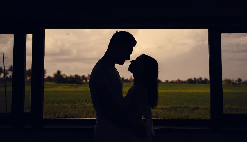 A silhouette of a couple standing in front of a window.