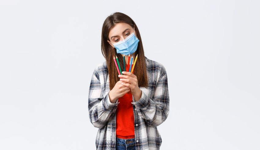A girl wearing a surgical mask while holding a pencil.