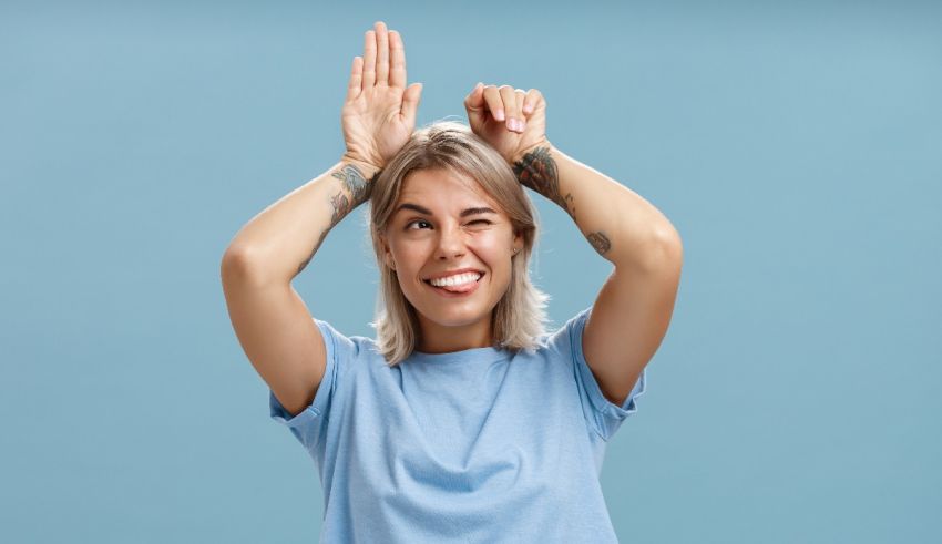 A young woman holding her hands up in the air over a blue background.