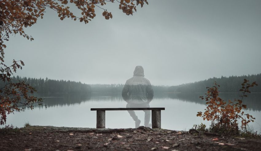 A person sitting on a bench in front of a lake.